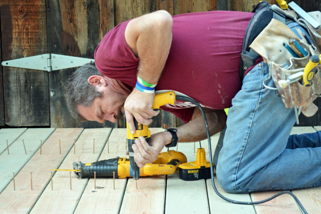 man screwing down boards for deck