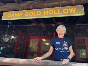 woman standing under Camp Gold Hollow sign